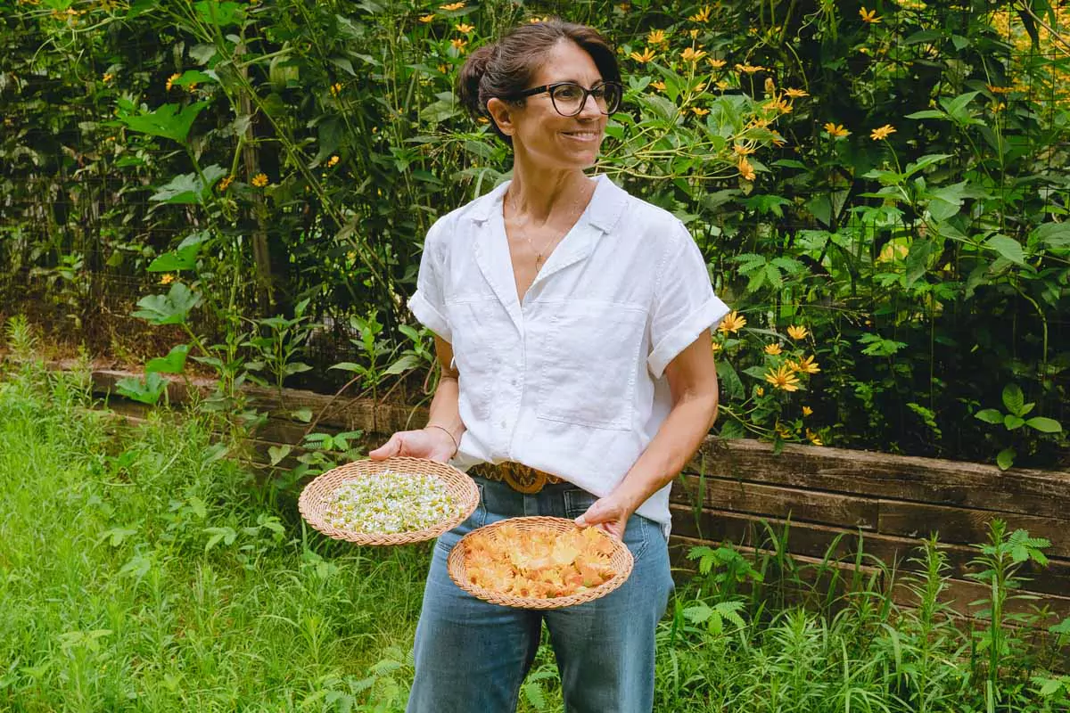 Annmarie holding baskets of harvested herbs in her garden